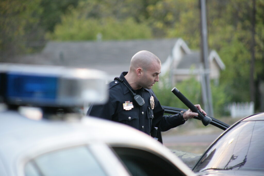 Chris Grollnek young McKinney Texas police officer on active duty scene black uniform badge radio squad car lights active shooter prevention expert before the mission aspppro.com history cannot be ignored